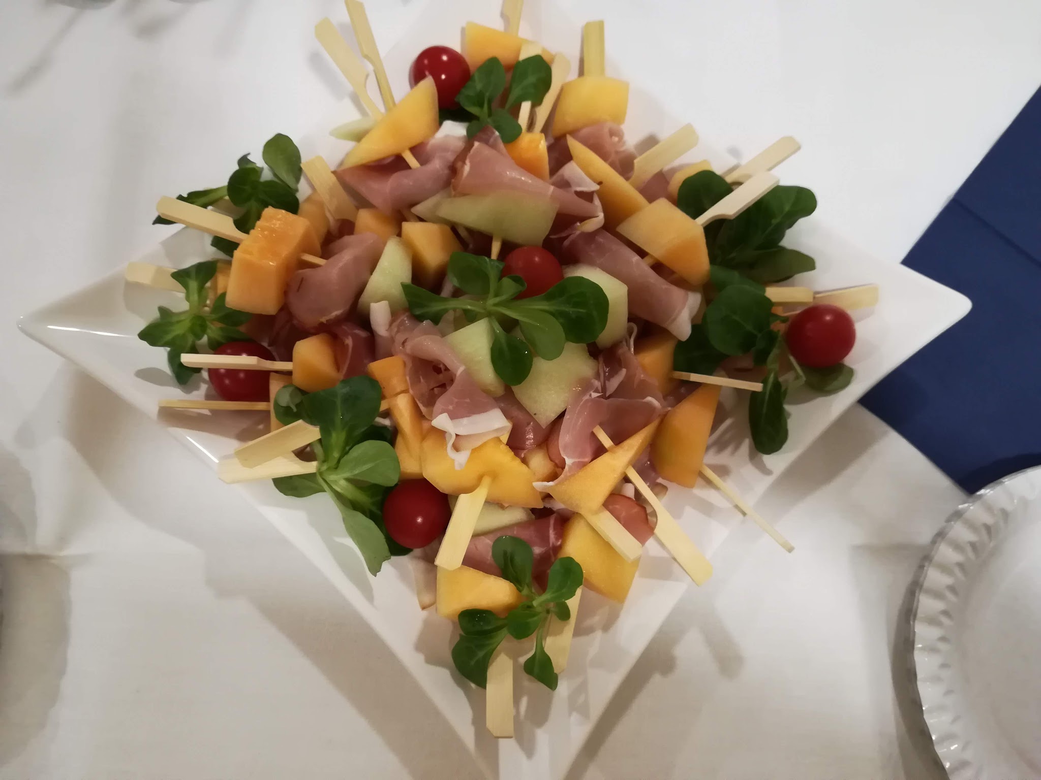 Schinken-Melonen-Spieße auf Salat angerichtet
